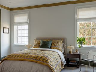 bedroom with white walls, yellow trims, grey bed with yellow throw pillows and quilt