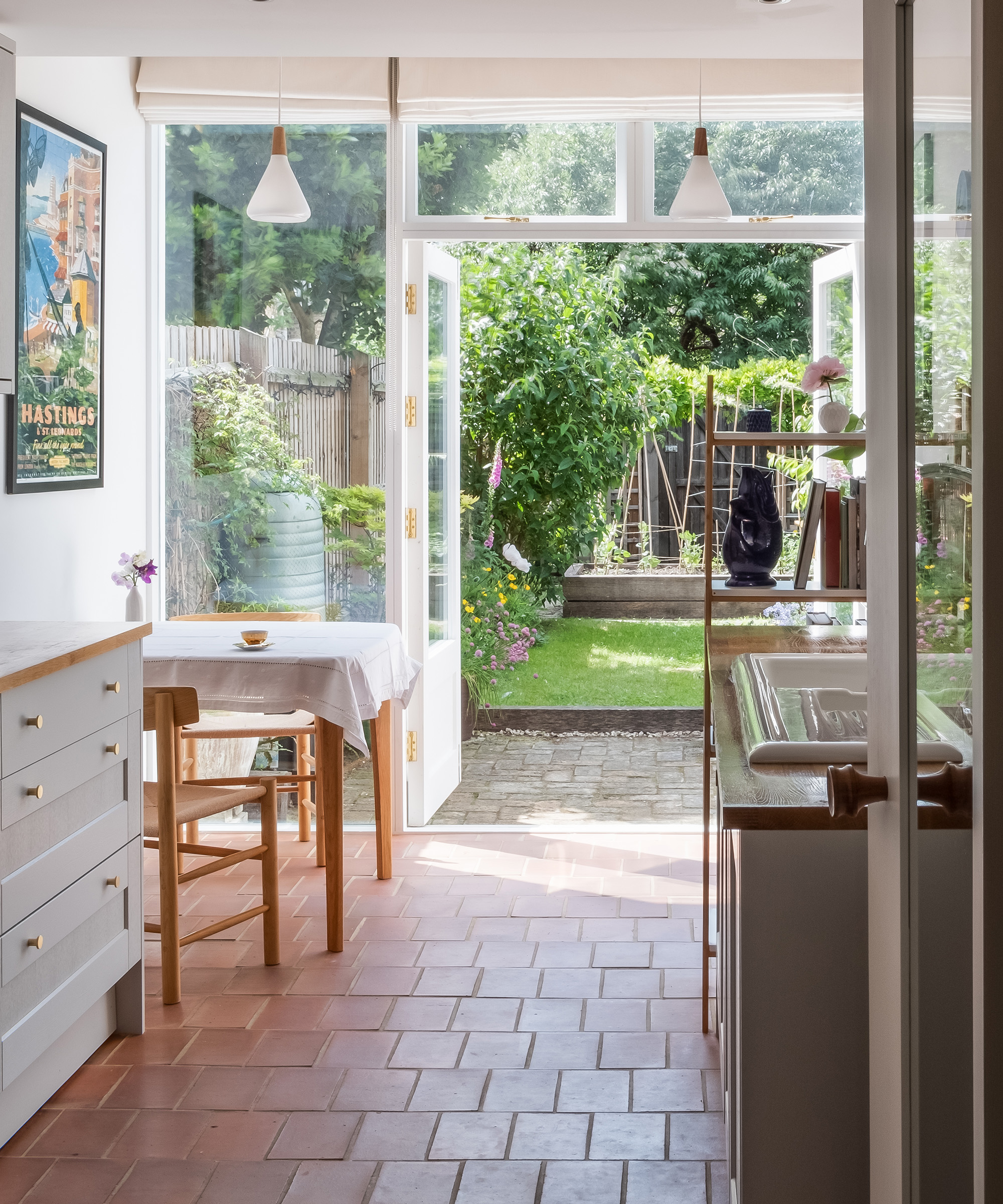 Open French doors leading out to a small terraced garden from a kitchen extension