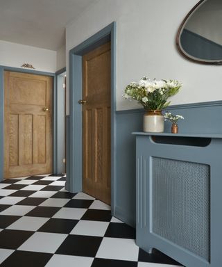 1930s style wooden doors in a hallway with blue painted panelling and chequered floor tiles