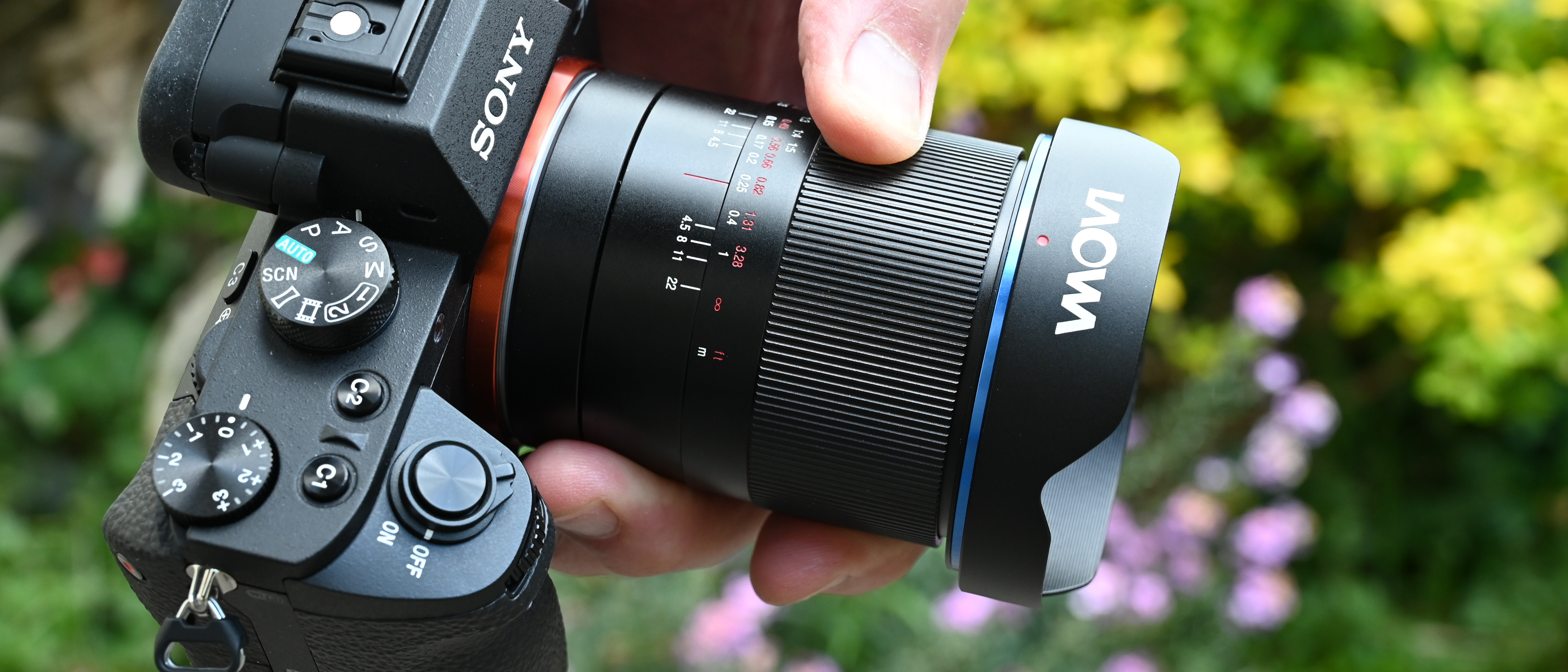 Laowa 15mm f/4.5 0.5x Macro product shot with lens held in hand