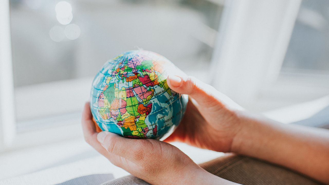 A pair of hands hold a small globe.