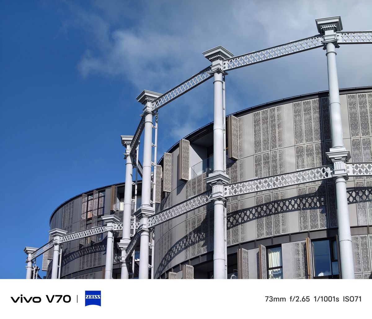 Telephoto architectural detail of Coal Drops Yard&rsquo;s white iron columns and patterned fa&ccedil;ade against sky.