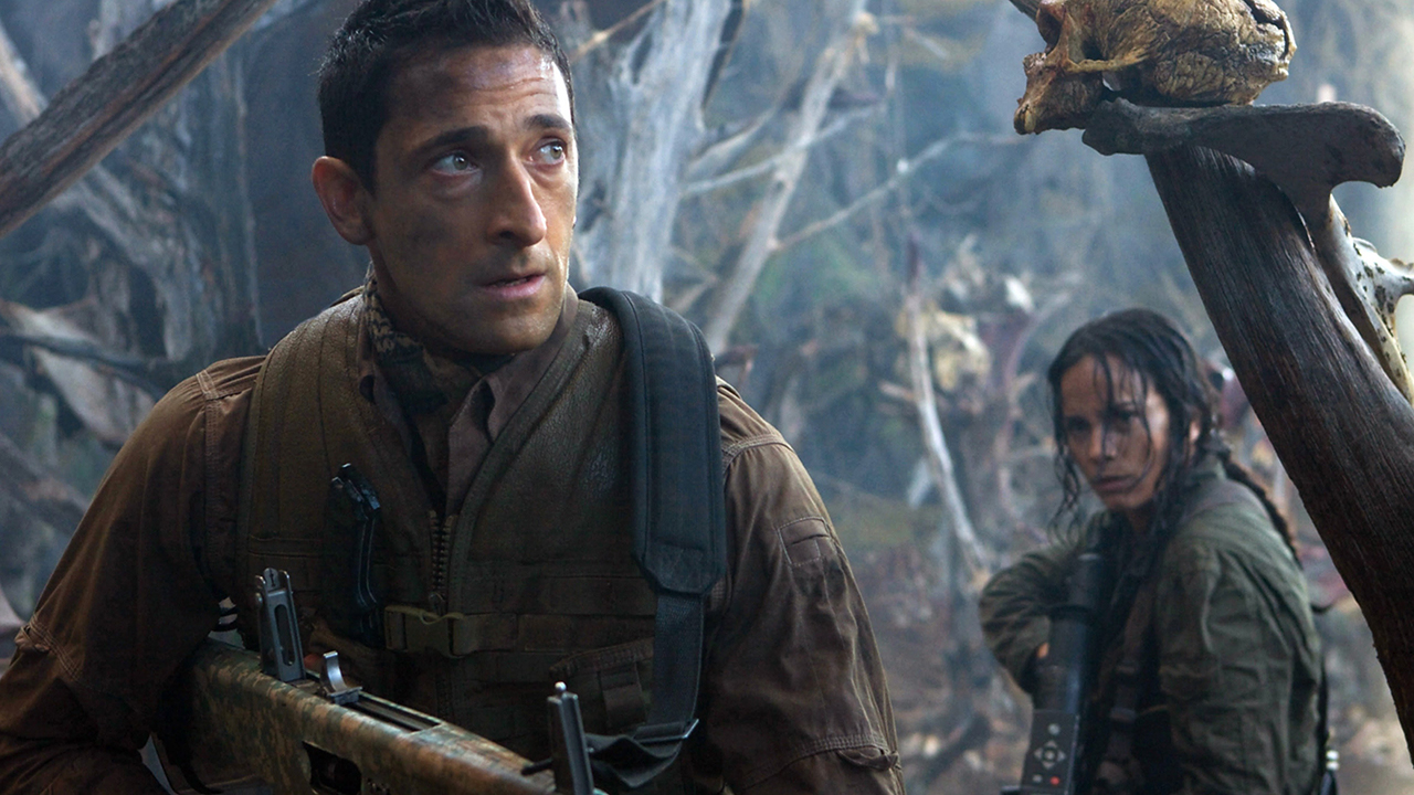 Still from the movie Predators.  Here we have a close up of a man and a woman holding guns wandering through a decaying forest.