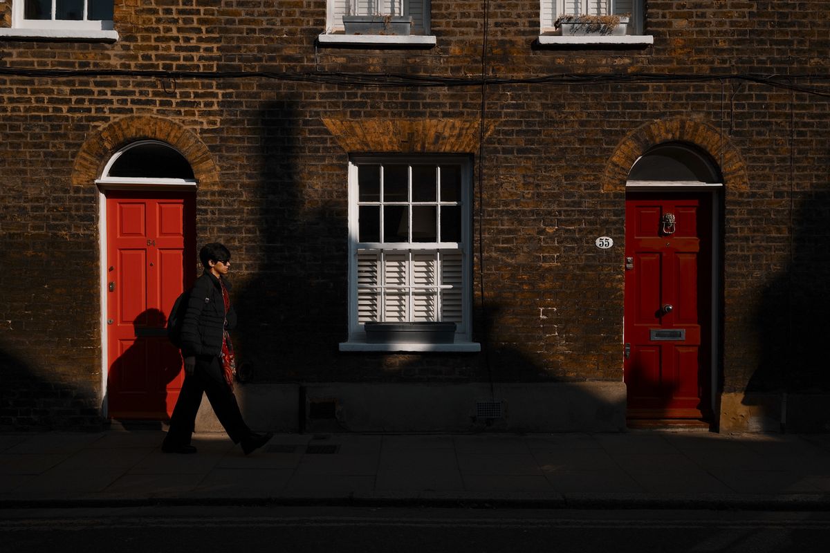 London street photo of people walking down old street in bright sunlight with strong shadows cast on the wall, taken with the Sigma BF camera and Sigma 35mm F2 DG lens