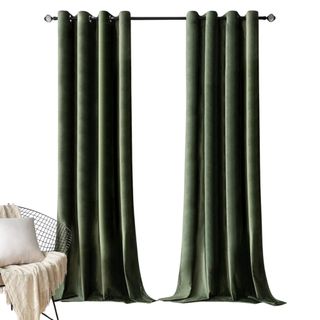 Green velvet curtains on a black curtain rod next to a silver metal chair with a beige blanket and white cushion