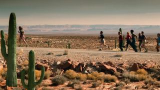 A group of runners on a stretch of highway in the desert.