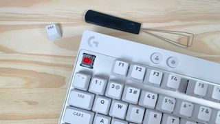 Close up of one of the switches on the white Logitech G PRO X TKL Rapid gaming keyboard beside a black keycap puller