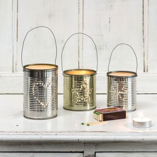 3 tin cans upcycled with holes and candles place inside them
