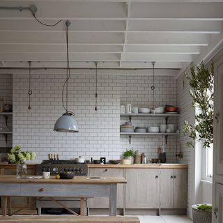 kitchen area with white wall tiles and wooden dining table with ceiling lamp