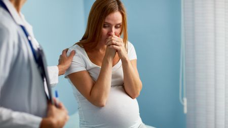 A pregnant woman at a doctor's appointment looks worried