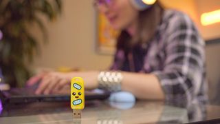 Image of the Peely drive standing on a desk with someone using a laptop blurred in the background.