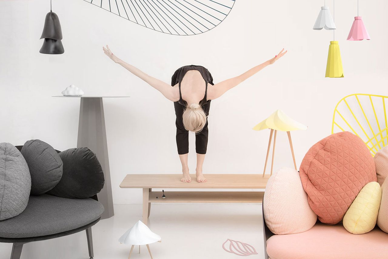 Woman standing on a wooden table and bending down with arms out