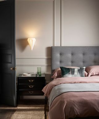 bedroom with gray headboard, pink bedding and black nightstand