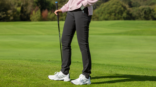 A golfer poses in the KJUS Women’s Warm Stretch Treggings