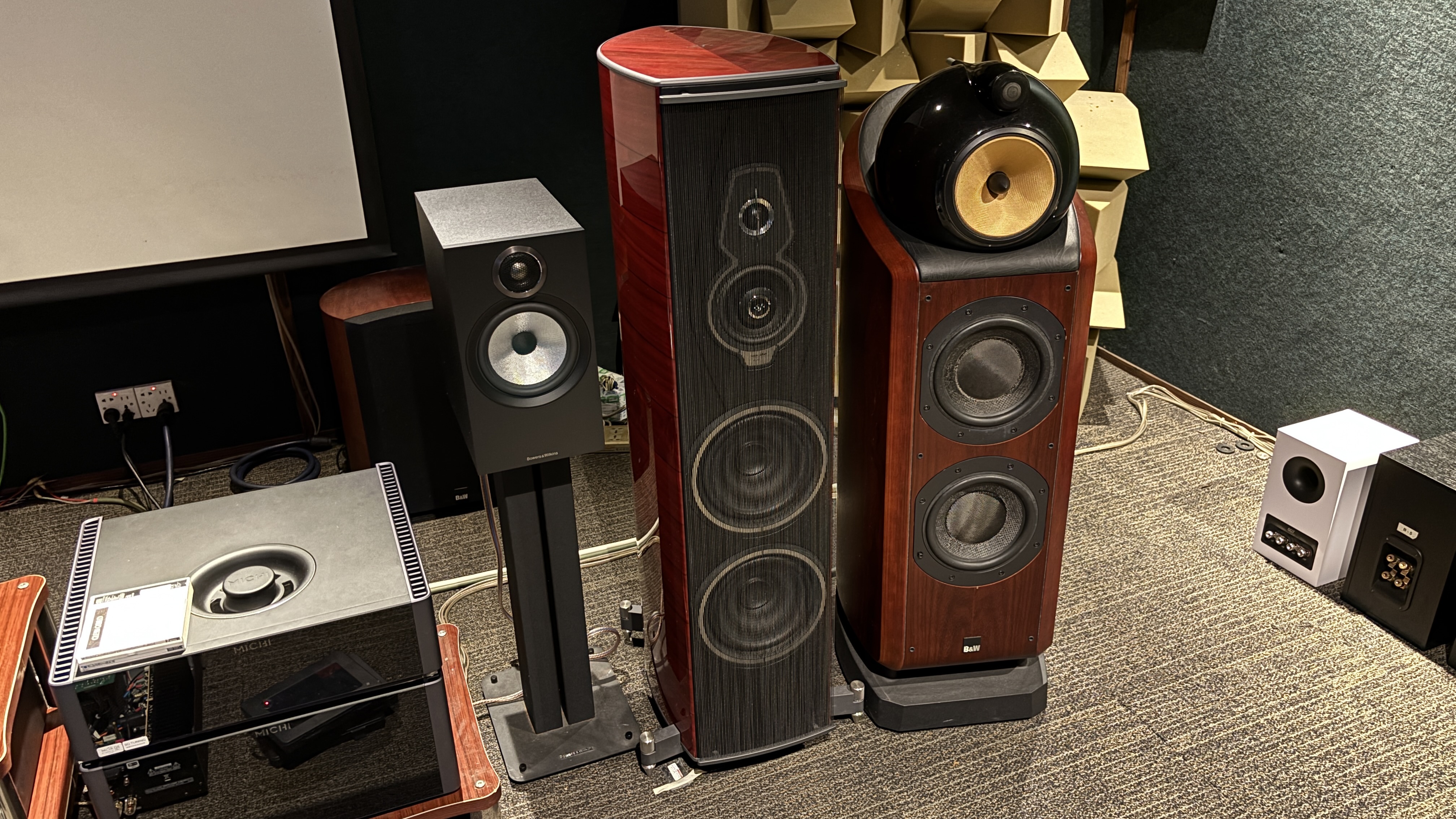 Three different speakers lined up in a test room next to Rotel Michi electronics