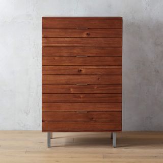 CB2 Linear Tall Wood Dresser against a gray wall.