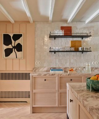 accent colors for a white kitchen, peach and white kitchen with pearlescent backsplash tiles, peach panelling and radiator over, blond wood and marble cabinetry, black metal open shelving