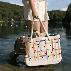 A colourful bogg bag being held by someone in a lake