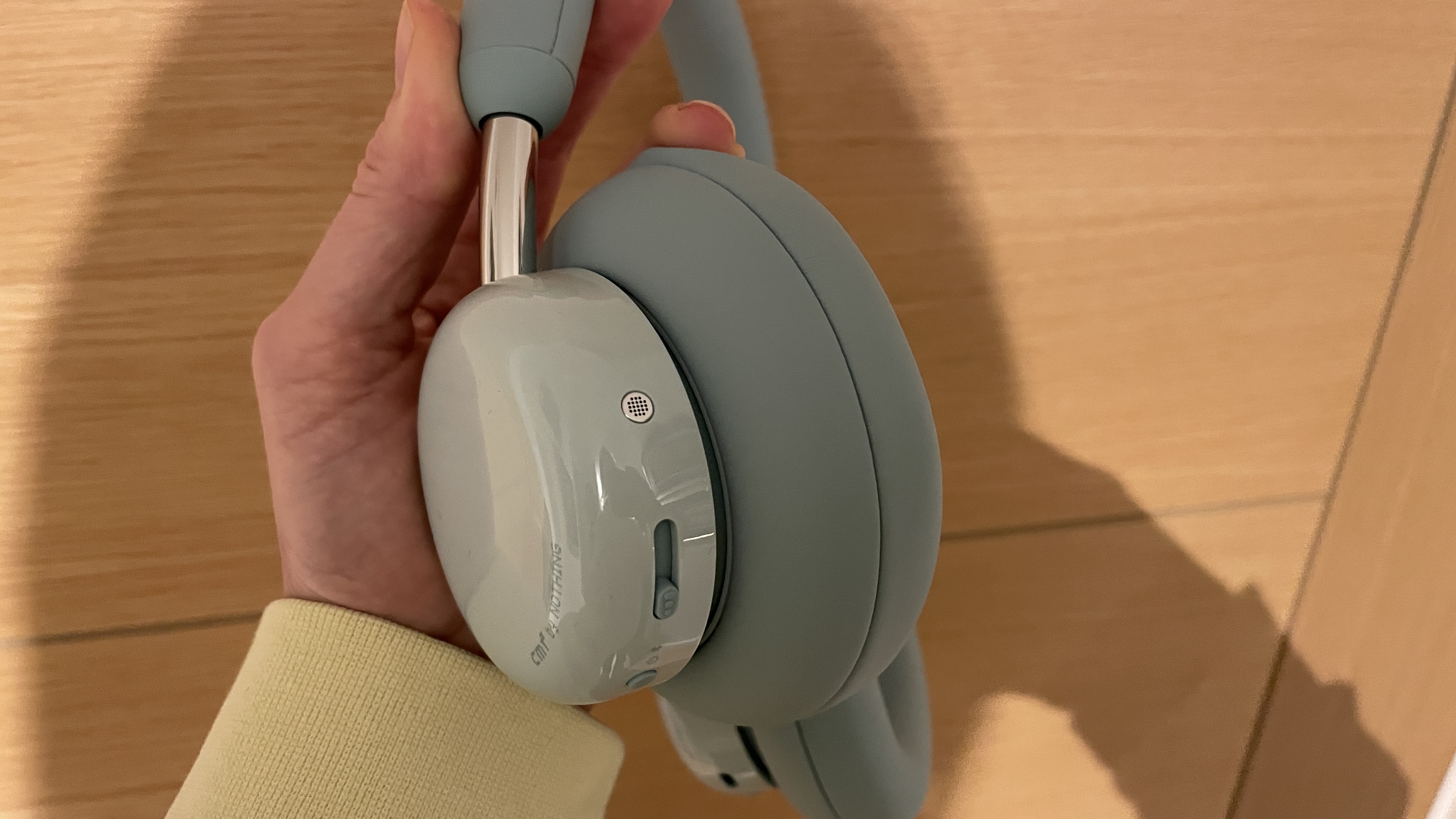 CMF Headphone Pro in pistachio green held in a hand or hung on a barbell, being pushed up by a carved frog