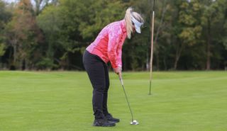 A golfer strikes a putt wearing the Puma DRYLBL Women's Golf Rain Pants