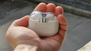 Samsung Galaxy Buds 3 Pro ligger i sitt tillhörande laddningsfodral i en öppen handflata.