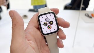 En hand som håller upp den nya Apple Watch SE 2 med ett vitt armband under Apple-lanseringen i september 2022.