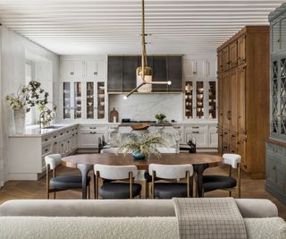 Open plan white kitchen with large oval dining table and a marble kitchen island