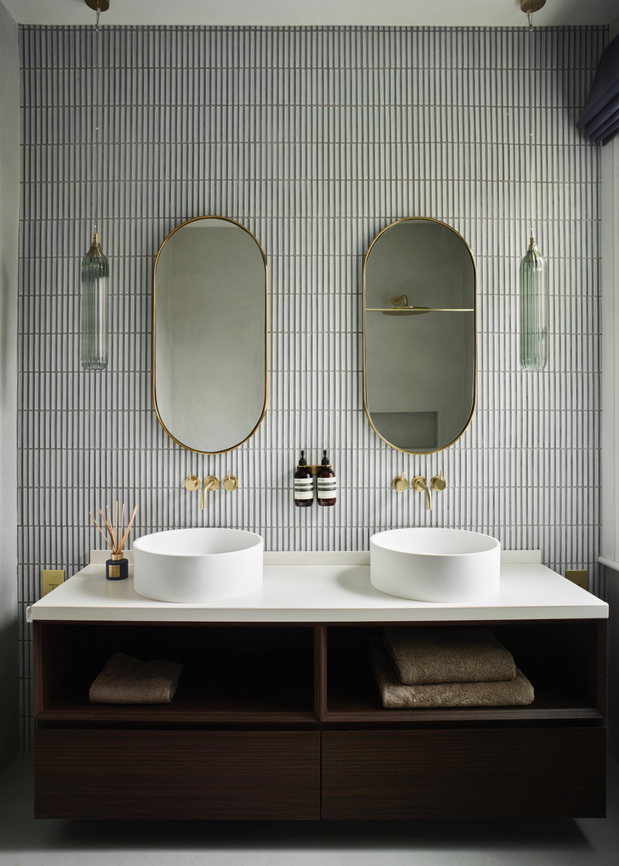 A bathroom with kitkat tiles and a large double vanity with circular sinks
