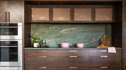A dark wood kitchen run along one wall with green stone worktop and backsplash