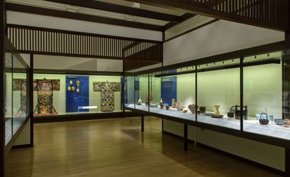 A museum with glass cases containing Japanese crockery and clothing.