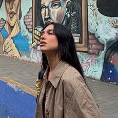 Dua lipa wearing a satin dress and trench coat