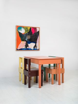 Table and chairs in different colours and artwork on wall