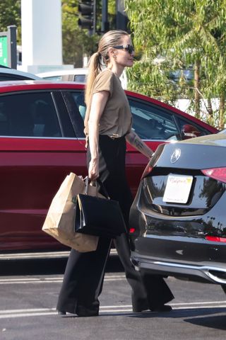 Angelina Jolie wearing a tan T-shirt, black trousers, and a black Clasp bag by Celine in Los Angeles.