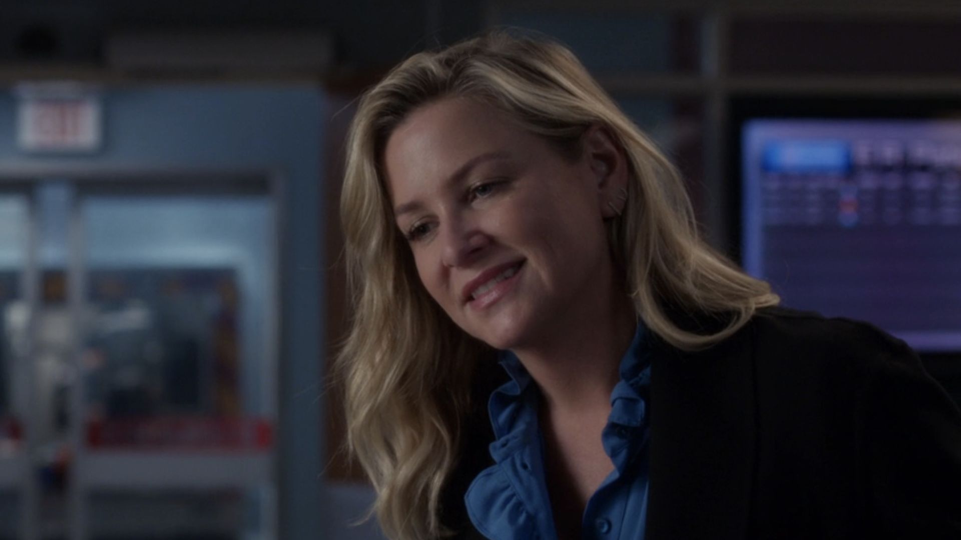 Arizona smiling in a blazer and blue shirt in the Grey's Anatomy ER.