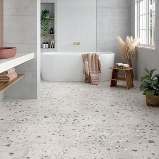 Terrazzo stone flooring in a spa-style bathroom with white freestanding bath tub