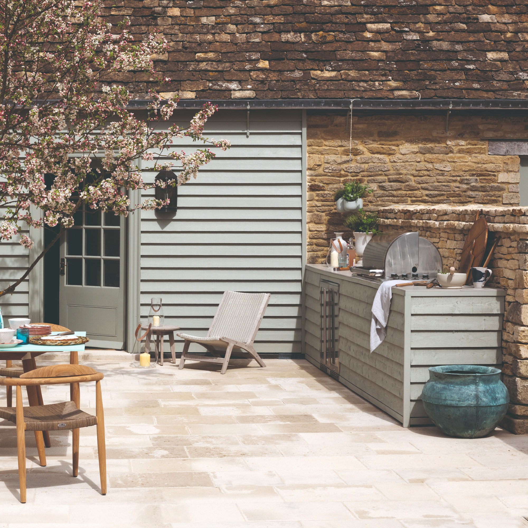 A patio with an outdoor kitchen and a cherry blossom tree