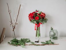 A glass vase with a red and green themed Christmas arrangement of flowers