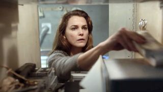 Keri Russell as Elizabeth Jennings reaching for some documents in a cupboard during the Hulu show, The Americans.