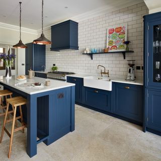 A blue kitchen with an island and pendant lights
