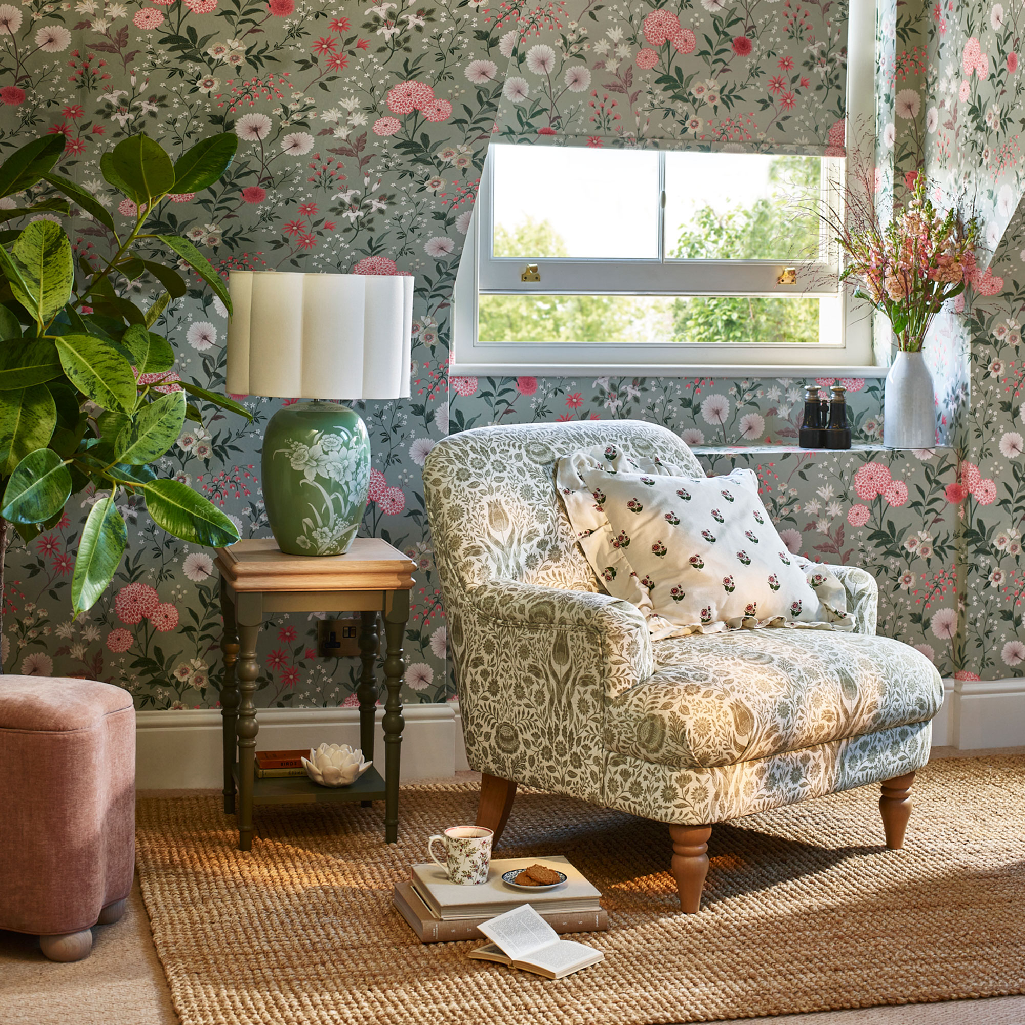 Green and cream patterned armchair in front of a floral wallpapered wall and open window