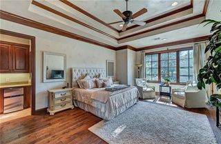 A master bedroom with a tray ceiling, wood accents, and a fluffy area rug