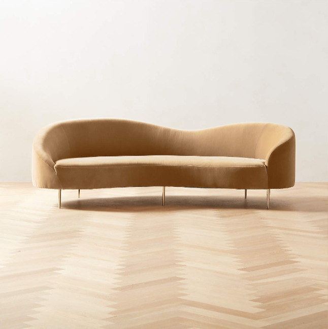 Curved tan velvet sofa by Goop.