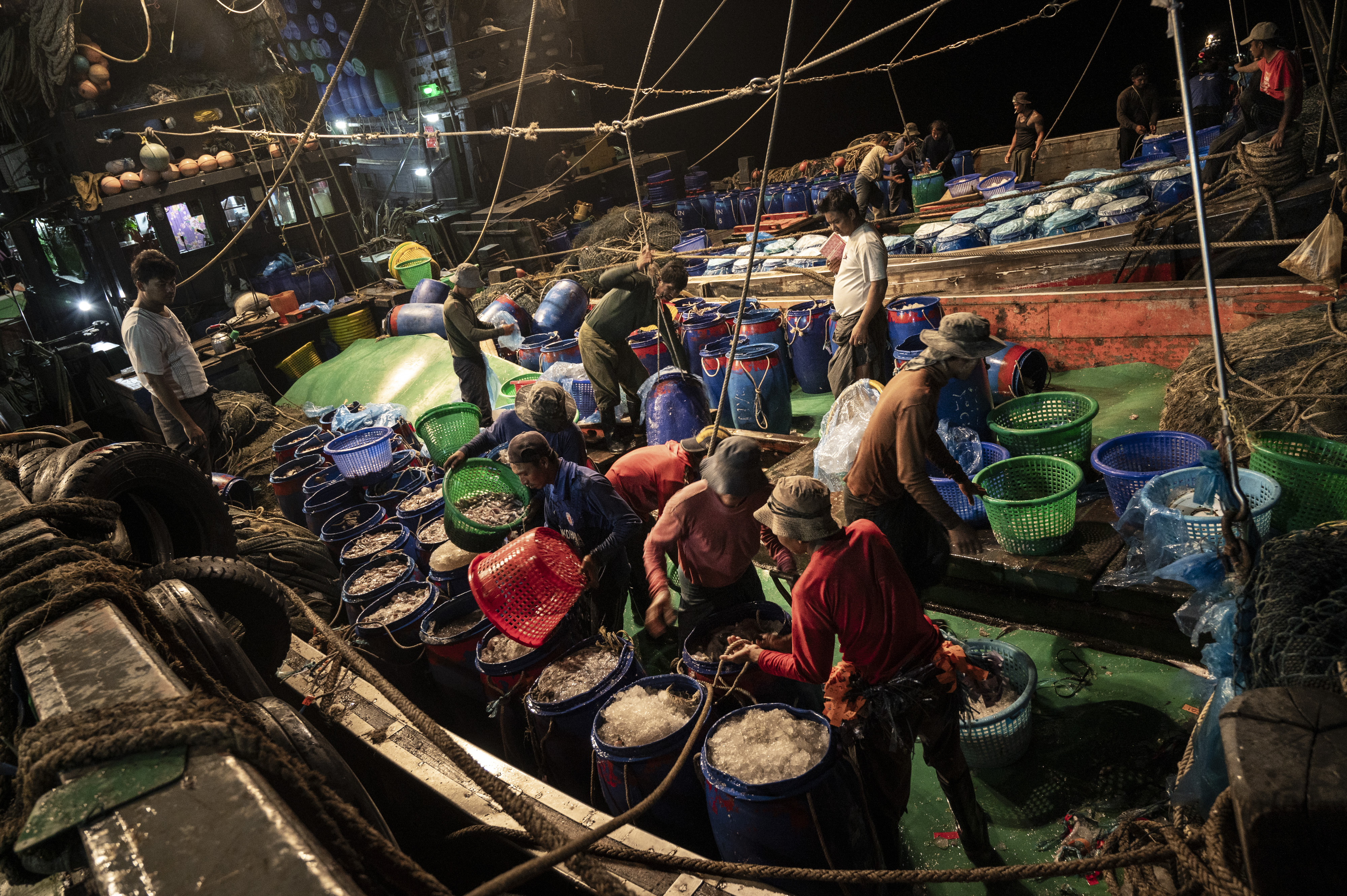 A room full with people unloading buckets of their catch.