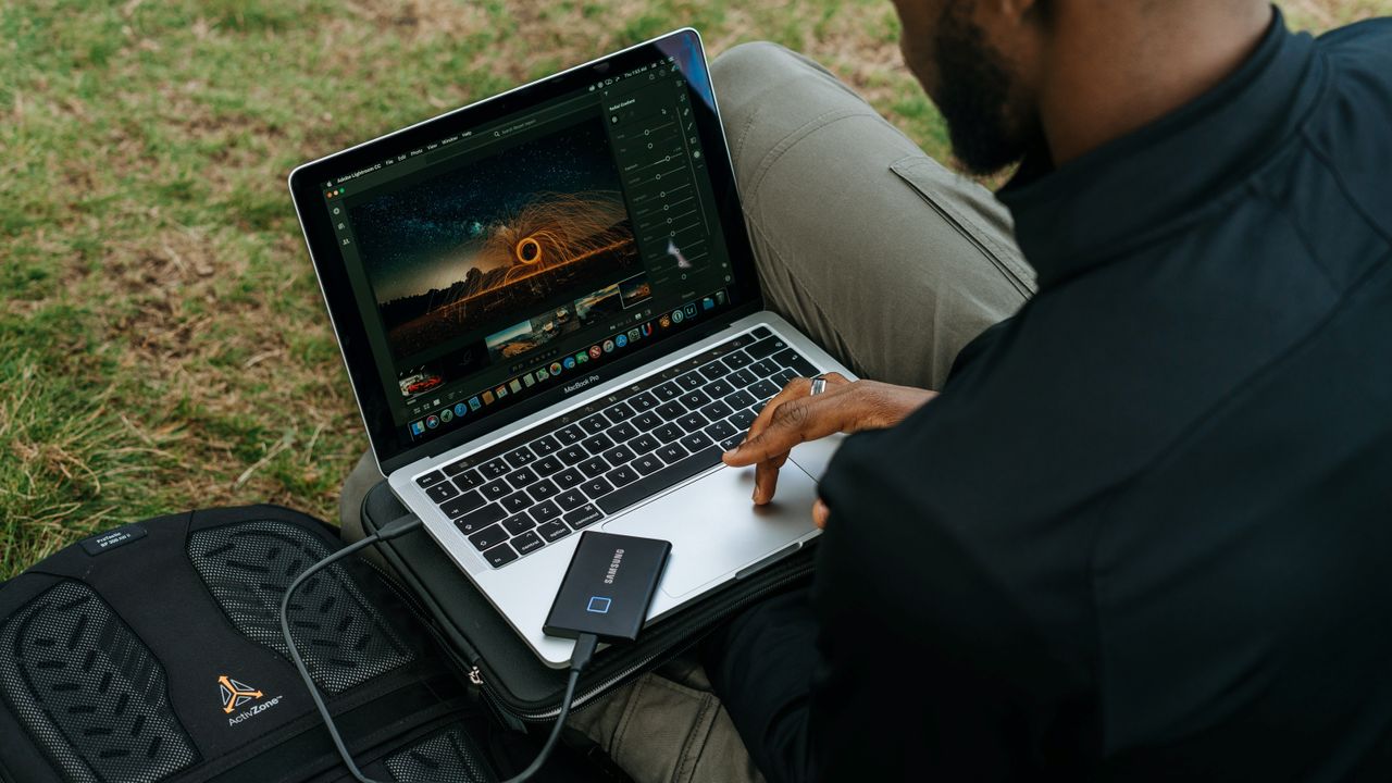 Best SSD: Man using laptop with Samsung portable SSD