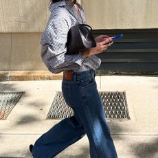 Woman in a button-down and jeans looking at her phone