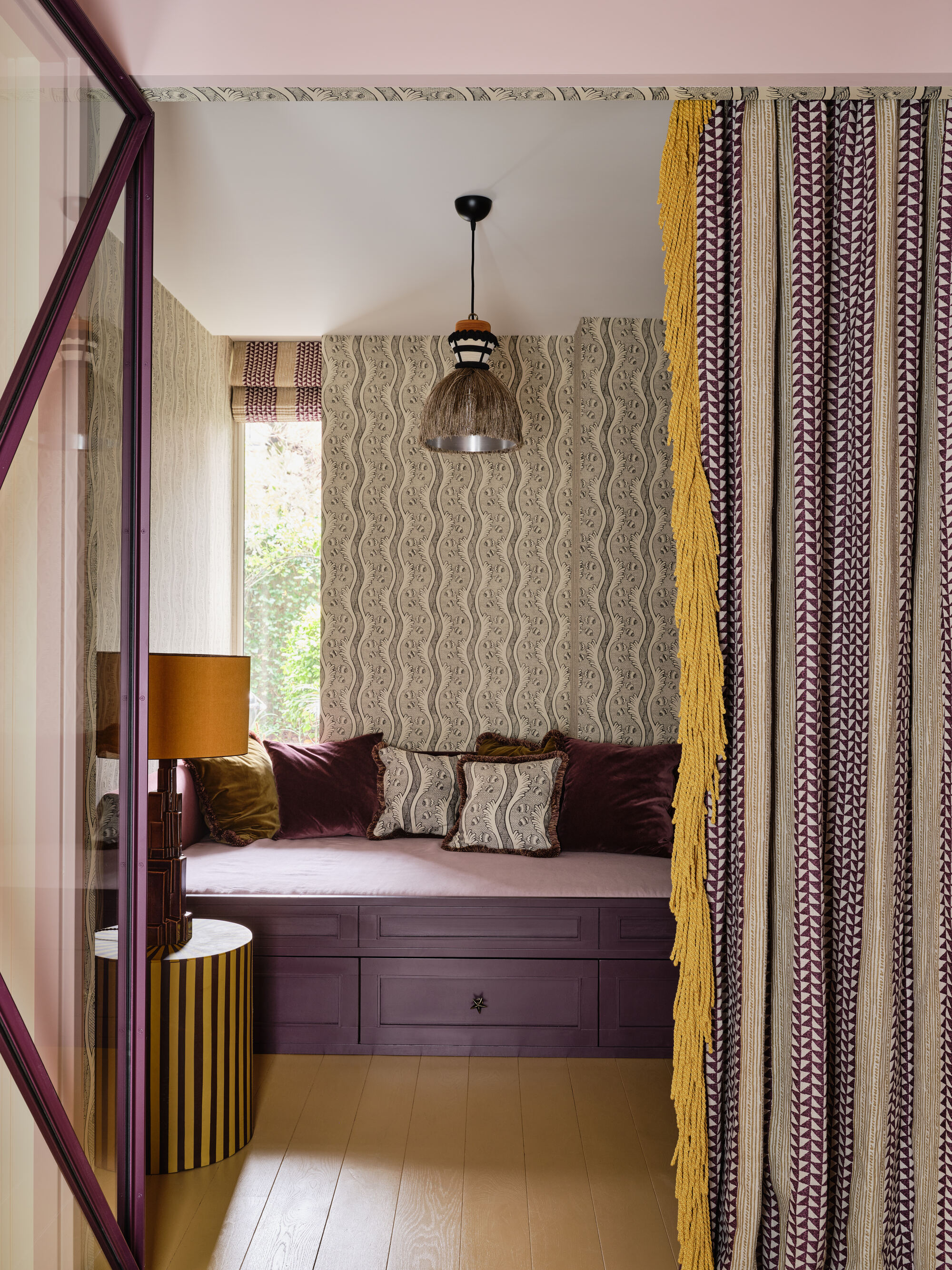 a purple and yellow bedroom with lilac sheets, purple accent cushions and black and white high contrast wallpaper