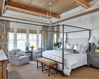 traditional bedroom with four-poster bed, gingham armchair, and wooden accents