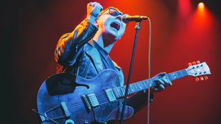 McKinley James plays his '59 Gibson ES-335 reissue with his fist in the air against a red background