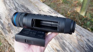 Pulsar Telos XQ35 monocular held in a hand outside in front of a log