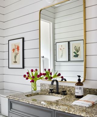 small bathroom with white clapboard walls and marble vanity top
